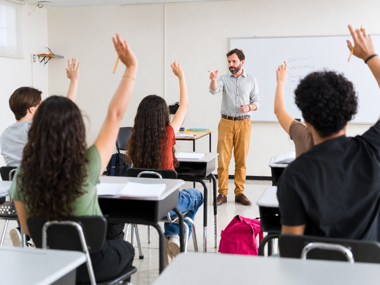 alumnos en clase con manos levantadas